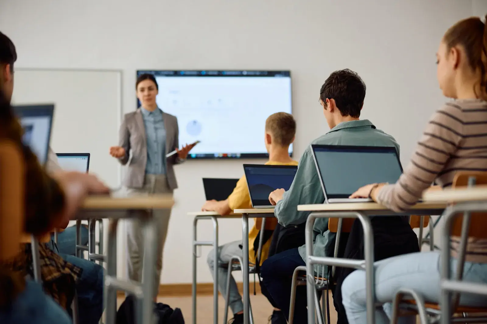 Instructor leading a training session while participants work on laptops